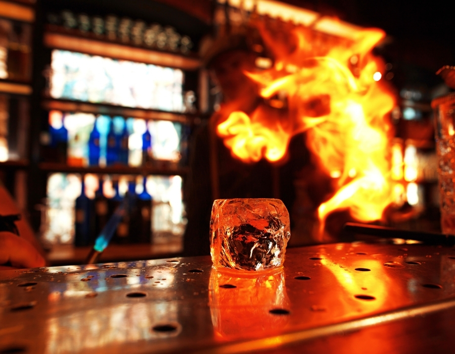 Ice cube on bar top with flames in background, highlighting alcohol service and bartending practices related to overserving alcohol.